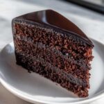 A close-up slice of Moist & Unique Chocolate Cake Design with rich, dark crumb and glossy ganache topping.