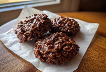 Three rich, dark No-Bake Chocolate Oat Cookies clustered together on a piece of white parchment paper.