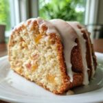 A moist slice of Peach Pound Cake featuring chunks of peach and topped with a thick Peach Pound Cake Almond Glaze.