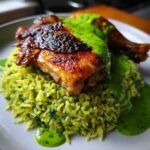 Close-up of crispy skin Peruvian Chicken and Rice with Green Sauce drizzled over the top.