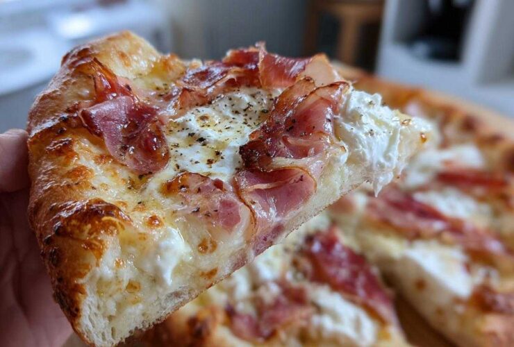 A close-up shot of a slice of Prosciutto Honey Burrata Pizza, showing melted cheese, ribbons of prosciutto, and dollops of creamy burrata.