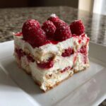 A perfect slice of Raspberry Tiramisu layered with cream, ladyfingers, and topped with fresh raspberries.