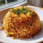 A perfectly molded mound of Savory Garlic Butter Crispy Rice, golden brown and topped with fresh chopped parsley, served on a white plate.