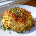 A perfectly molded mound of Savory Garlic Butter Crispy Rice with a dark, caramelized crust, topped with fresh parsley.