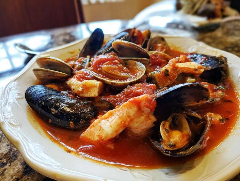A close-up of a bowl of rich seafood Cioppino featuring mussels, clams, and shrimp in a vibrant tomato broth.