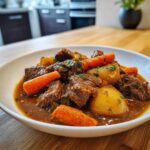A close-up of tender Slow Cooker Beef Stew featuring chunks of beef, carrots, and potatoes in a rich brown gravy.