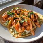 Close-up of three Spicy Sriracha Mayo Shrimp Tacos topped with creamy sauce and cilantro.