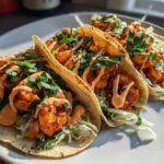 Three delicious Spicy Sriracha Mayo Shrimp Tacos filled with seasoned shrimp, shredded cabbage, and drizzled with sauce.