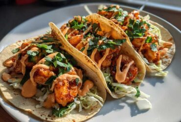 Three delicious Spicy Sriracha Mayo Shrimp Tacos filled with seasoned shrimp, shredded cabbage, and drizzled with sauce.