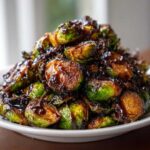 A mound of roasted Brussels sprouts generously coated in a dark, shiny Sticky Brussels Sprouts Glaze.