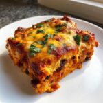 A close-up of a cheesy slice of Sweet Potato and Black Bean Enchilada Casserole topped with fresh cilantro.