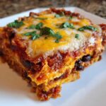 A close-up serving of Sweet Potato and Black Bean Enchilada Casserole topped with melted cheese and cilantro.