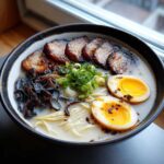 A rich bowl of Tonkotsu Ramen with Chashu, soft-boiled eggs, and black garlic oil.