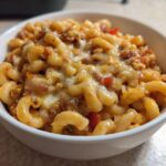 Close-up of a white bowl filled with cheesy Vegetarian Chili Mac, featuring elbow macaroni and melted cheese topping.