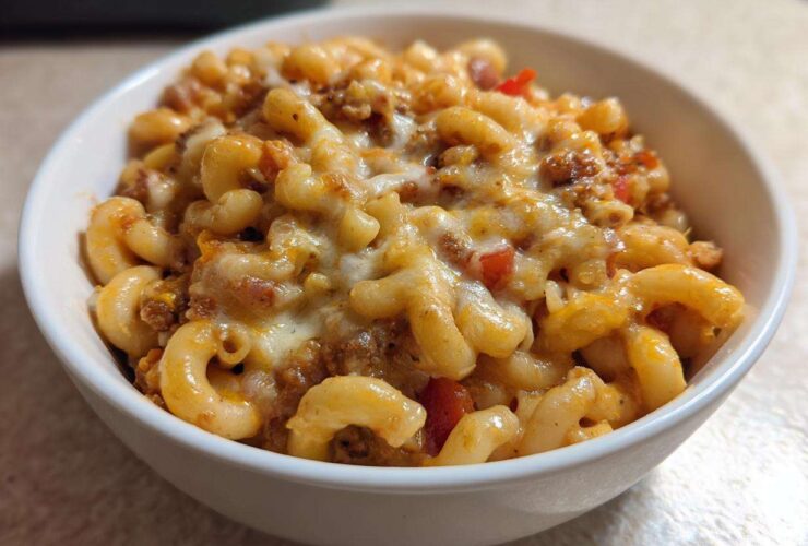 Close-up of a white bowl filled with cheesy Vegetarian Chili Mac, featuring elbow macaroni and melted cheese topping.
