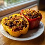 Two halves of colorful Vegetarian Stuffed Bell Peppers Dinner, one yellow and one red, filled with quinoa, black beans, and corn.