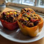 Three colorful Vegetarian Stuffed Bell Peppers Dinner halves filled with quinoa, beans, and corn, served on a white plate.