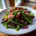 Close-up of a vibrant three Bean Salad featuring bright green beans, dark red kidney beans, and chopped red onion.