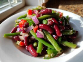 Close-up of a vibrant Bean Salad featuring kidney beans, green beans, red onion, and red peppers on a white plate.