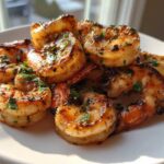 Close-up of perfectly grilled Zesty Lime Cilantro Grilled Shrimp piled on a white plate, garnished with fresh herbs.